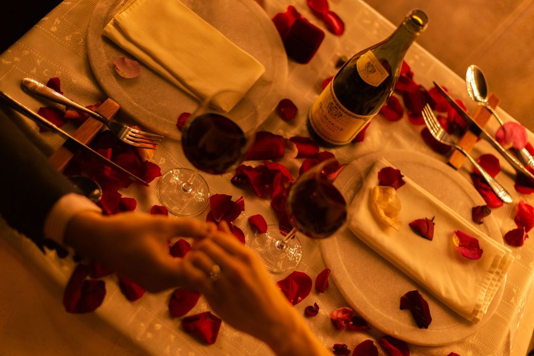 Hands joined across a dinner table with rose petals