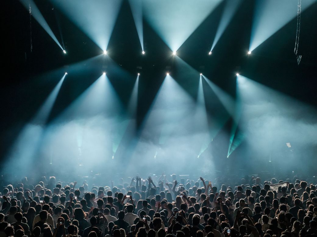 A concert crowd under stage light beams