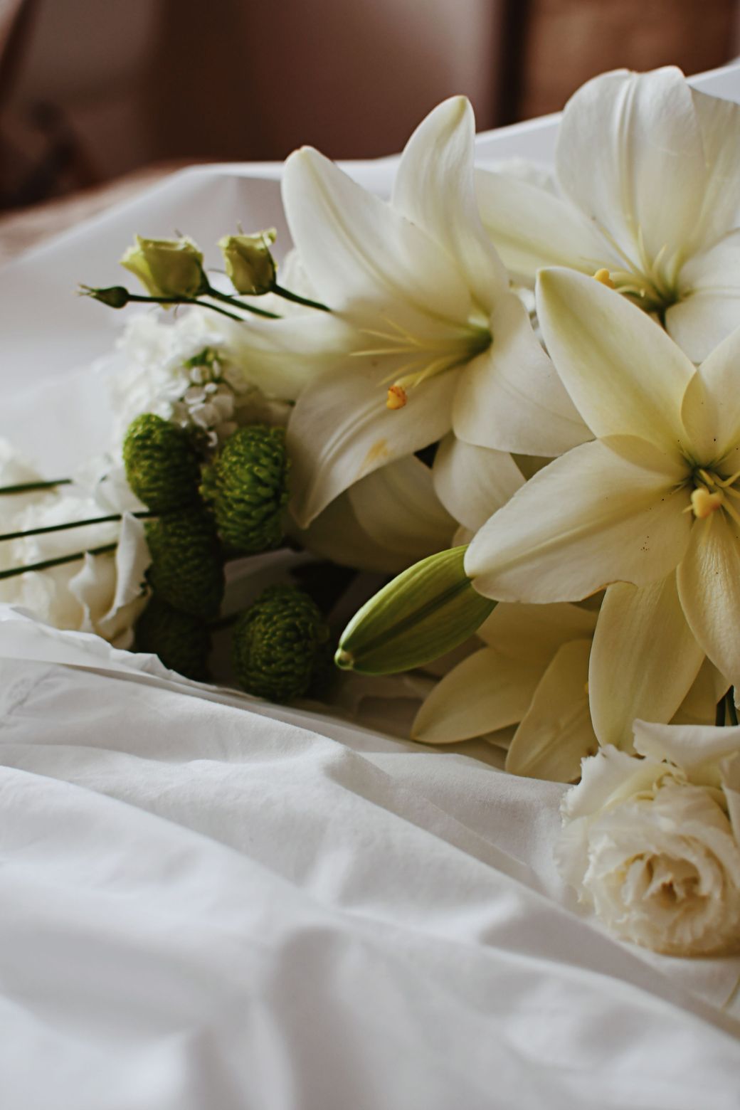 White lilies resting on white fabric