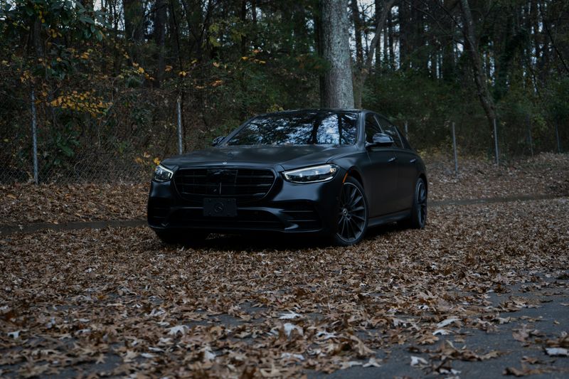 A black Mercedes-Benz S-Class on a leaf-covered road
