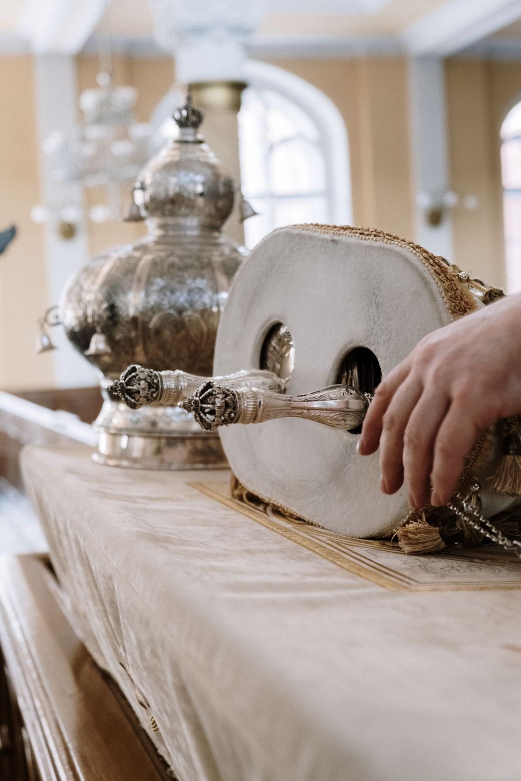 A Torah scroll and silver finials on a table in a synagogue
